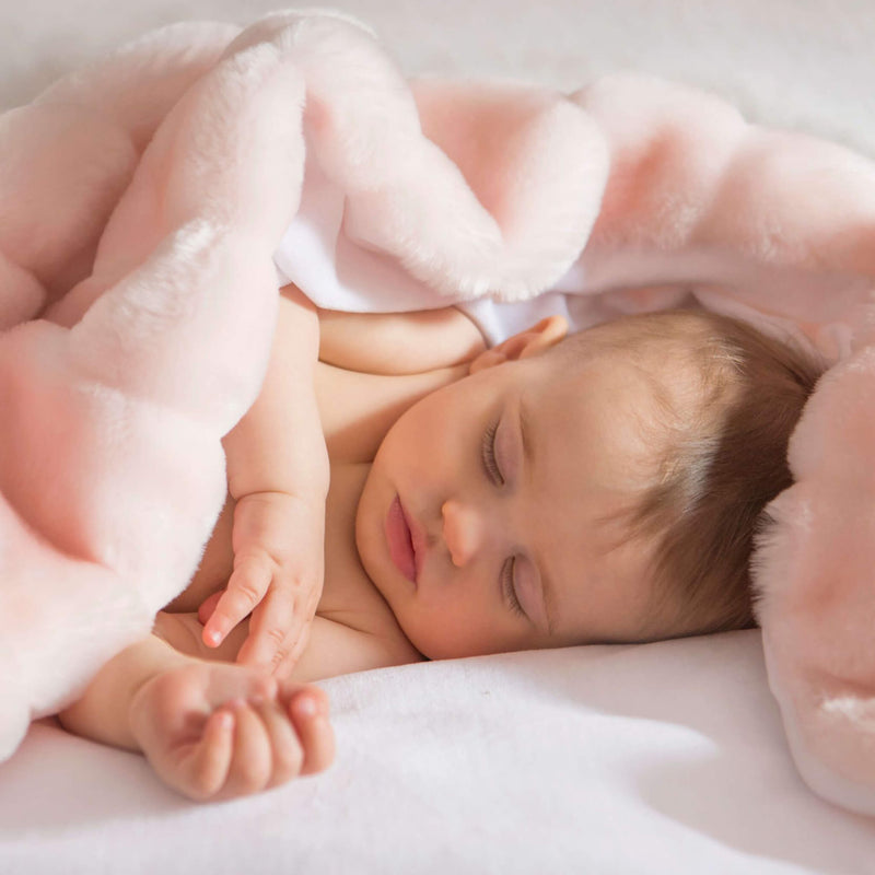 A sleeping infant wrapped in a pink minimink faux fur throw blanket