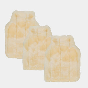three faux fur milk faux fur hot water bottle covers on cream background